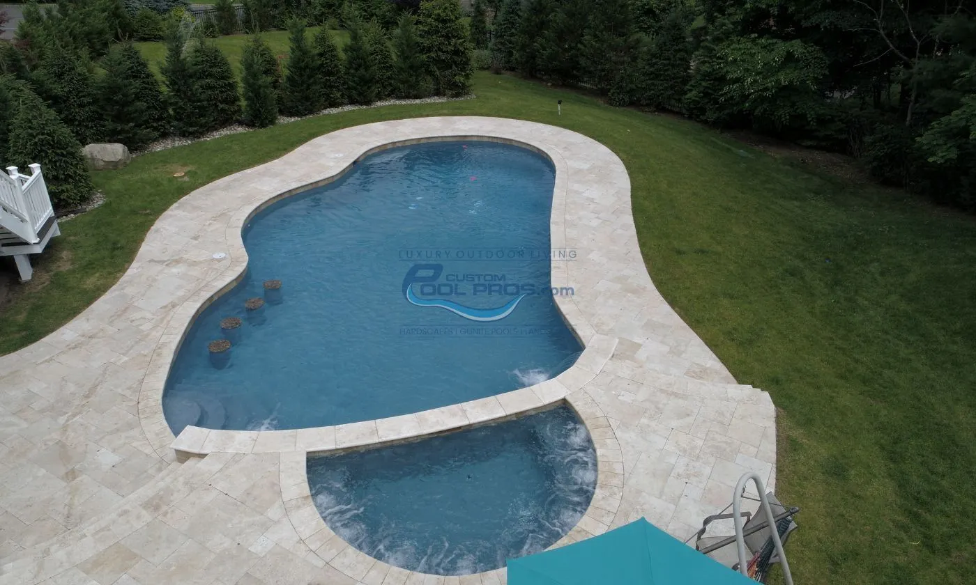 freeform inground gunite concrete pool with 4 in water seat stools, spa with jets turned on, pool deck built with travertine tile, pool installation nj
