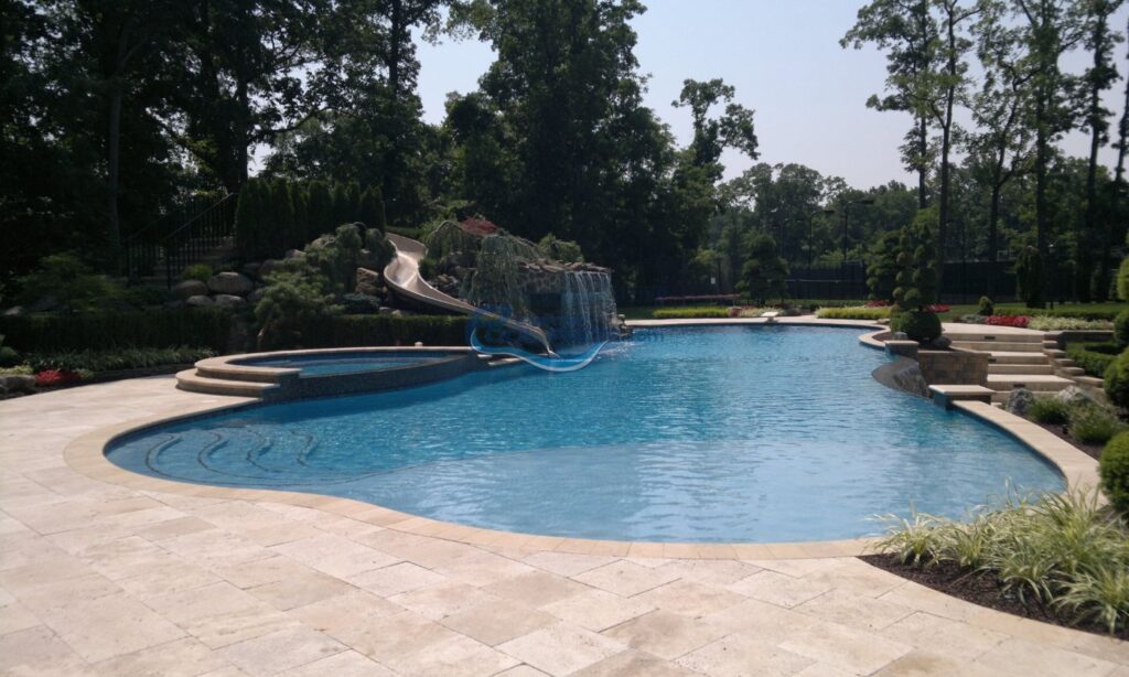 inground pool with spa, waterfall grotto, slide and vanishing edge, travertine pool patio deck installation, pool company nj